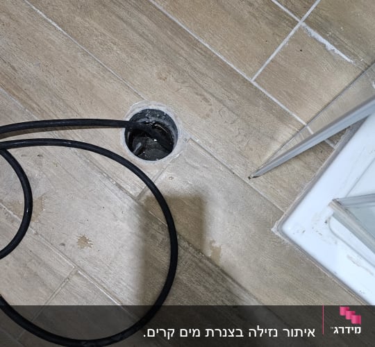 כבל שחור נכנס לניקוז ברצפה